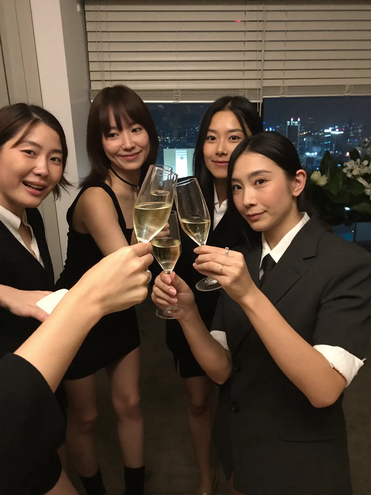 夜景を背にシャンパンで乾杯する同僚たち